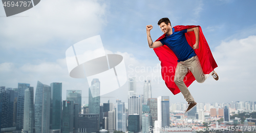 Image of man in red superhero cape flying in air over city