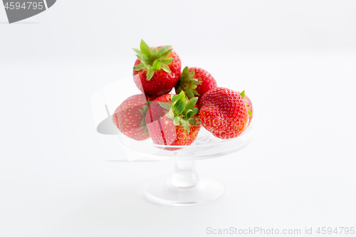 Image of strawberries on glass stand over white background