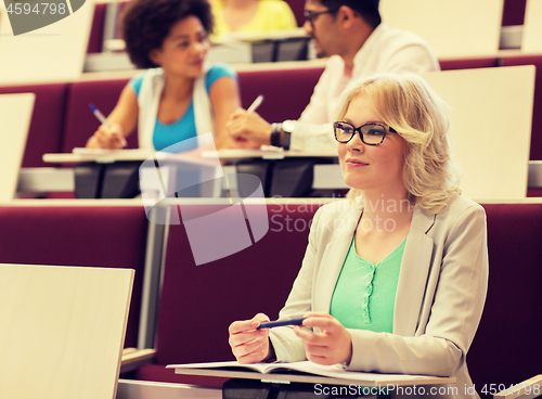 Image of student girl writing to notebook in lecture hall