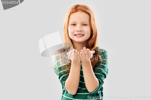 Image of smiling red haired girl holding something on palms