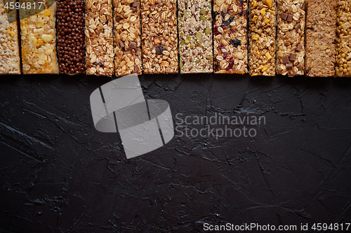 Image of Various healthy granola bars placed in a row on black stone table