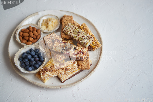 Image of Mixed composition of energy nutrition bar, granola on ceramic plate over white background