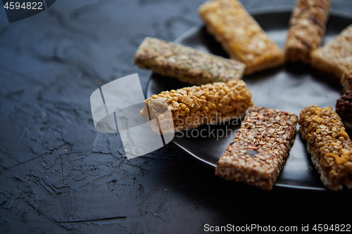 Image of Different kind of granola fitness bars placed on black ceramic plate on a table