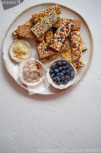 Image of Mixed composition of energy nutrition bar, granola on ceramic plate over white background