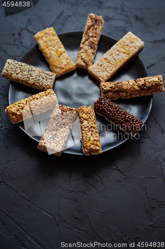 Image of Different kind of granola fitness bars placed on black ceramic plate on a table