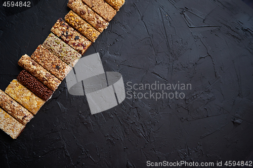 Image of Various healthy granola bars placed in a row on black stone table