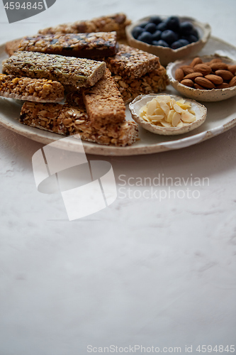 Image of Mixed composition of energy nutrition bar, granola on ceramic plate over white background