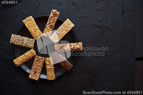 Image of Different kind of granola fitness bars placed on black ceramic plate on a table