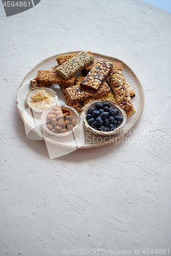 Image of Mixed composition of energy nutrition bar, granola on ceramic plate over white background