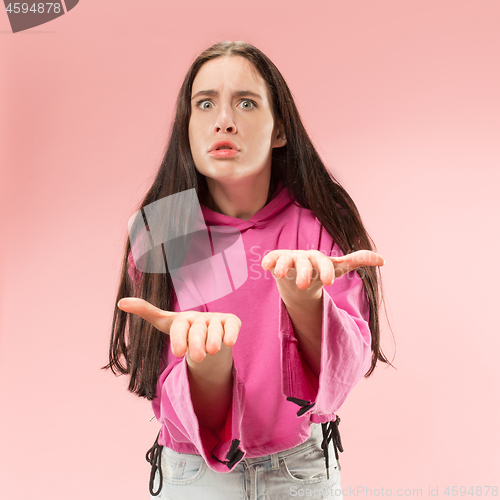 Image of Beautiful female half-length portrait isolated on pink studio backgroud. The young emotional surprised woman