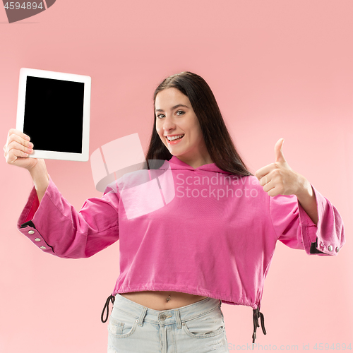 Image of Portrait of a confident casual girl showing blank screen of laptop isolated over pink background