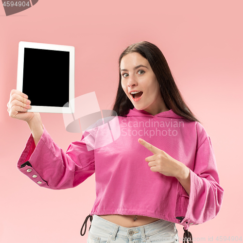 Image of Portrait of a confident casual girl showing blank screen of laptop isolated over pink background