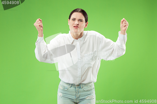 Image of Beautiful female half-length portrait isolated on green studio backgroud. The young emotional surprised woman