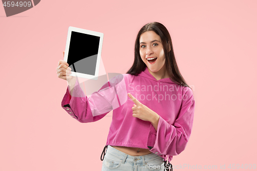 Image of Portrait of a confident casual girl showing blank screen of laptop isolated over pink background