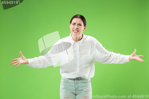 Image of Beautiful female half-length portrait isolated on green studio backgroud. The young emotional surprised woman