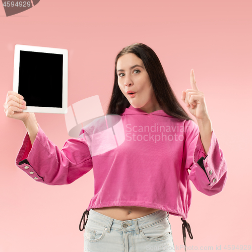 Image of Portrait of a confident casual girl showing blank screen of laptop isolated over pink background