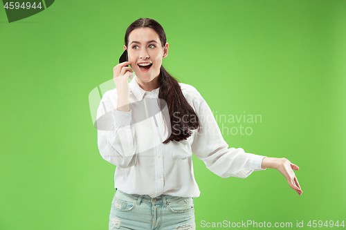 Image of Young beautiful woman using mobile phone studio on green color background