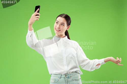 Image of Portrait of a happy smiling casual girl showing blank screen mobile phone isolated over green background