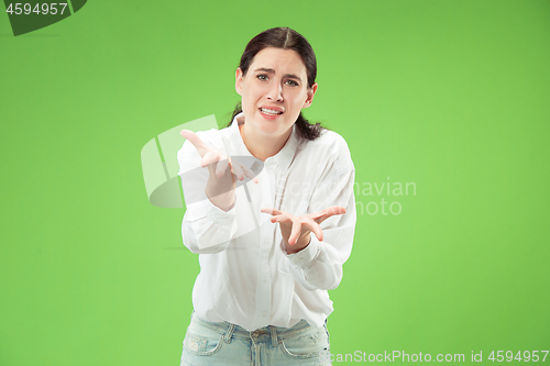 Image of Beautiful woman looking suprised and bewildered isolated on green