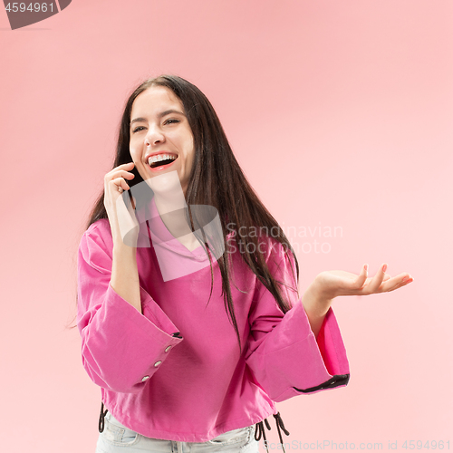Image of Young beautiful woman using mobile phone studio on pink color background