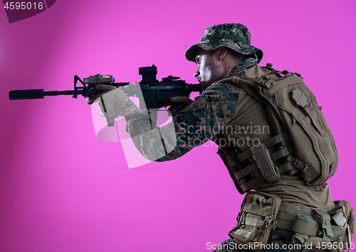 Image of soldier in action aiming laseer sight optics pink background