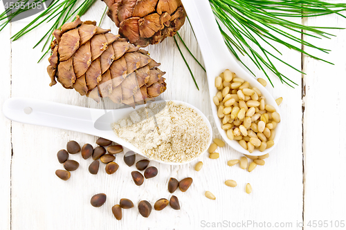 Image of Flour cedar and nuts in two spoons on board top