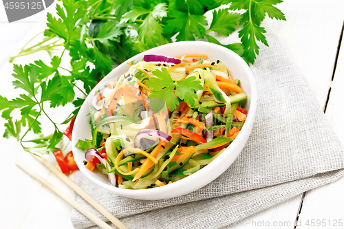 Image of Salad of cucumber in bowl on light wooden board