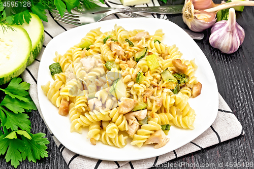 Image of Fusilli with chicken and zucchini in plate on dark wooden board