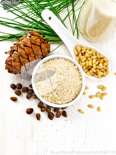 Image of Flour cedar in bowl and nuts in spoon on white board top