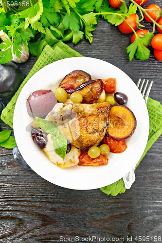 Image of Chicken with fruits and tomatoes in plate on dark board top