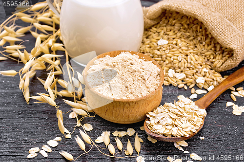 Image of Flour oat in bowl with oatmeal on dark wooden board