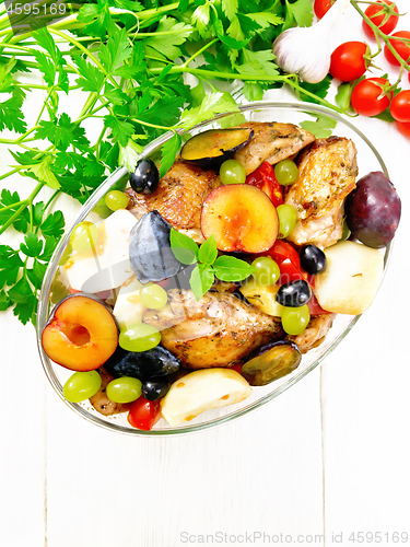 Image of Chicken with fruits and tomatoes in pan on light board top