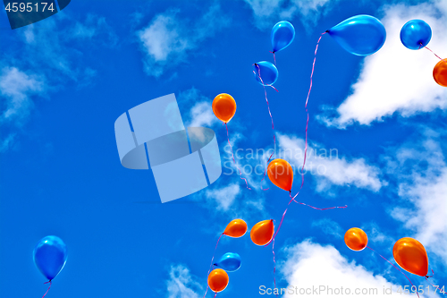 Image of Balloons orange and blue in sky with clouds