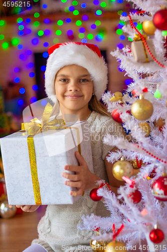 Image of Beautiful girl with a big New Year\'s gift against the background of blurred lights