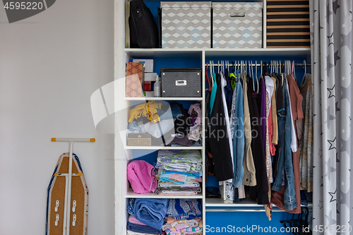 Image of A cupboard with the usual sloppy man\'s belongings, next to it stands an ironing board