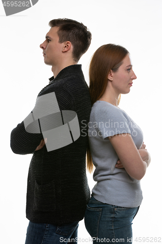 Image of A man and a woman stand with their backs to each other, with their arms folded on their chests
