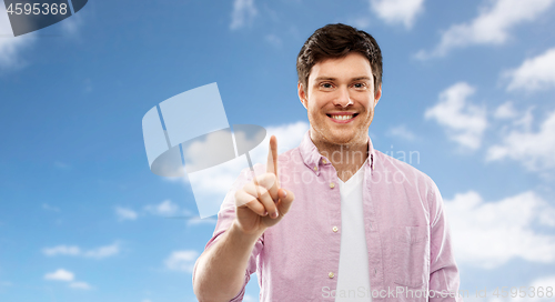 Image of young man showing one finger over blue sky