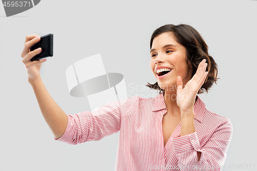 Image of smiling young woman taking selfie by smartphone