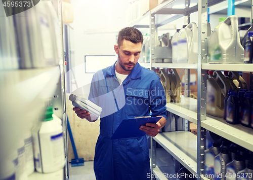 Image of auto mechanic with oil and clipboard at car shop