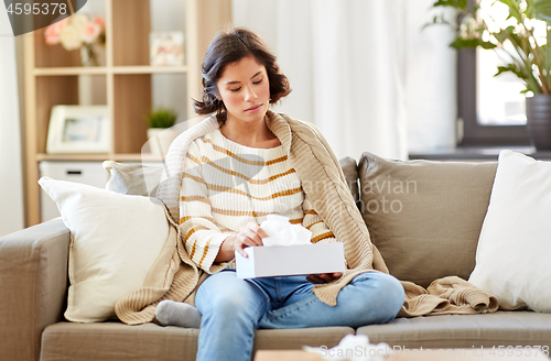 Image of sick woman taking paper tissue from box at home