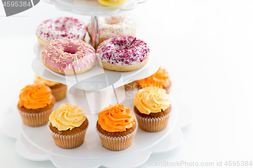 Image of glazed donuts, cupcakes with frosting on stand