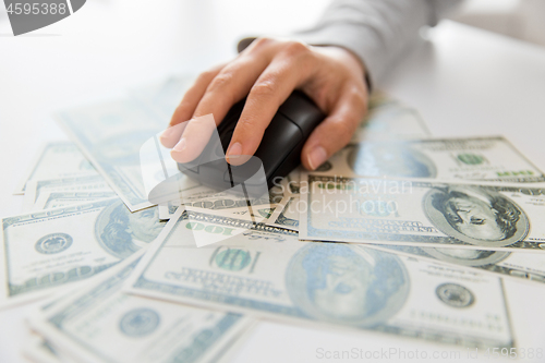 Image of close up of hand with computer mouse on money