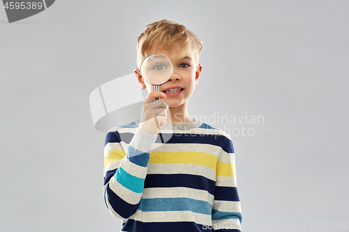 Image of curious boy looking through magnifying glass