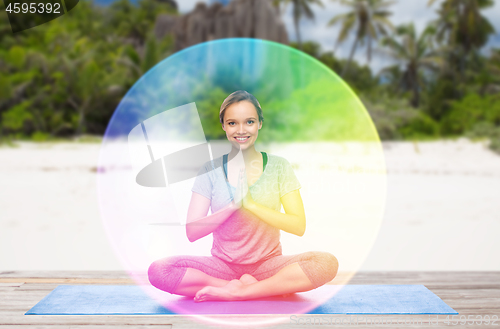 Image of woman doing yoga in lotus pose with rainbow aura