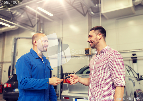 Image of auto mechanic giving key to man at car shop