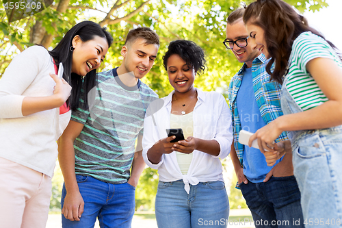 Image of happy friends with smartphones at summer park