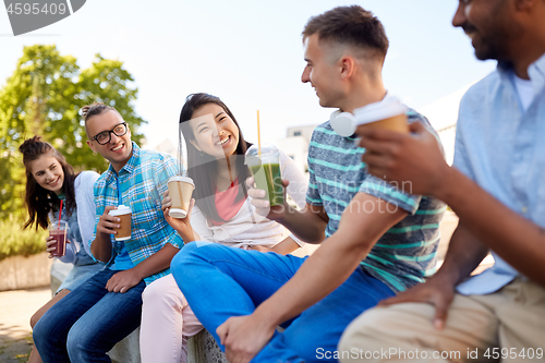 Image of friends drinking coffee and juice talking in city