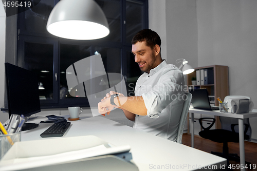 Image of happy businessman using smart watch at nigh office