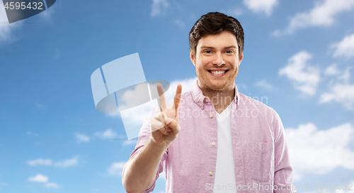 Image of man showing two fingers or peace sign over sky