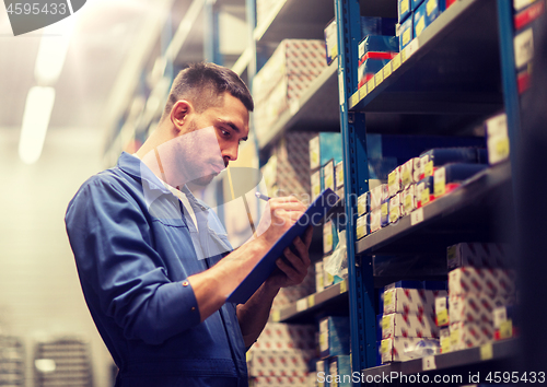 Image of auto mechanic with clipboard at car workshop